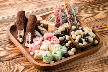 set of sweet candies with nuts and candied fruits on a wooden tray