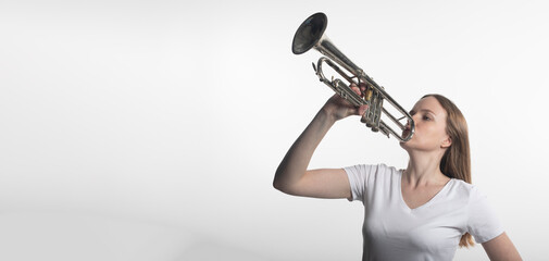 young caucasian woman holding trumpet and playing it isolated on white background, copy space