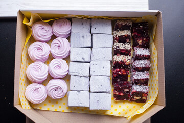 Marshmallows in craft paper packaging. Zephyr in the form of a rose. On black background.