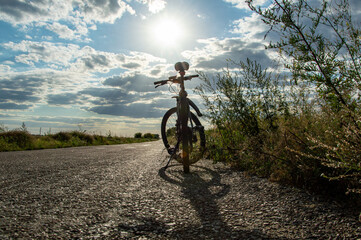 Fototapeta na wymiar Mountain bike on the asphalt road, cycling, road and bike on the background of the sun