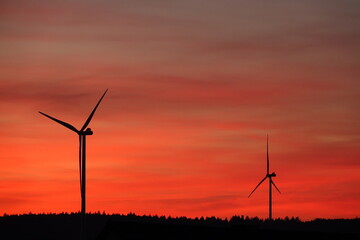 Zwei Windräder am roten Abendhimmel im Schatten