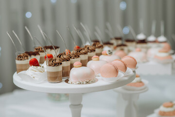 Fototapeta na wymiar Candy bar. Dessert table with delicious cupcakes, pink macaroons, cakes, marshmallows. Strawberry on the top of marshmallow
