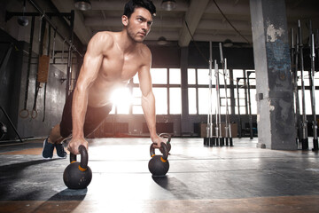 Fototapeta na wymiar Handsome muscular man doing pushup exercise with dumbbell in a crossfit workout