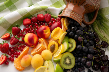 A colored rainbow of berries and fruit spilled out of the jug. The concept of healthy eating. Top...