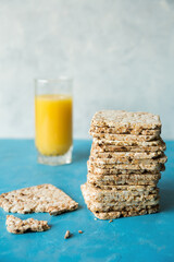 Delicious, diet loaves in a stack on a blue background close up. A glass of orange juice with crunchy crackers. Healthy food.