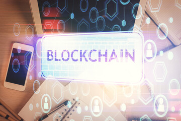Blockchain theme hologram drawings over computer on the desktop background. Top view. Double...