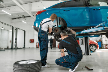 Auto care is our responsibility. Full length shot of two male mechanics using torch for examining...