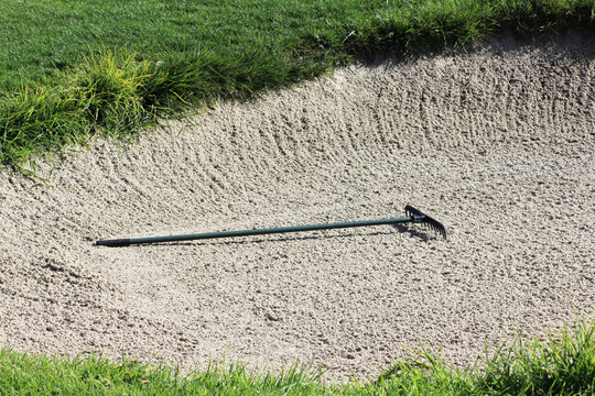 Gold sand rake laying in a bunker