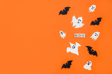 Word Boo. Wooden blocks with lettering on orange background decorated with bats and ghosts from cardboard. Halloween banner, copy space