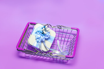 Top view of a small shopping basket with a gift box on a pink background