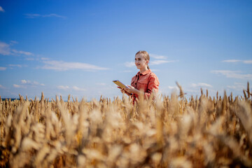 Woman caucasian technologist agronomist with tablet computer in the field of wheat checking quality and growth of crops for agriculture. Agriculture and harvesting concept.
