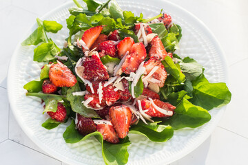 Summer salad with strawberries on a white plate and a light background. Close up. Place for copy space