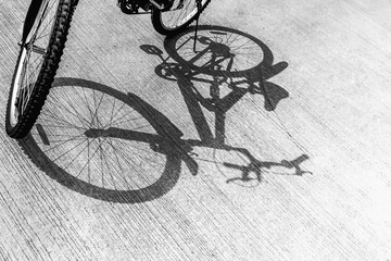 Black and white image of a bicycle parked on the cement floor, with a shadow leading down, health, energy-savings and reduce pollution concept.