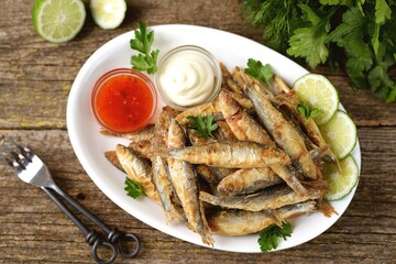 Grilled little fish in cornmeal and lime. On an old wooden background.