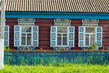 Vintage wooden ornamental carved windows, frames on facade of rustic folk house. Belarus