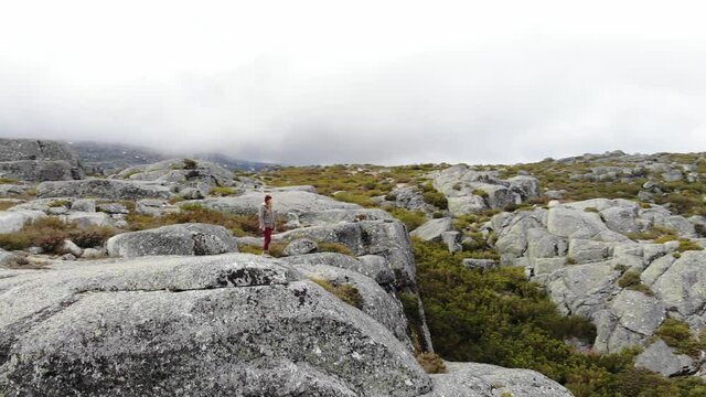 Aerial drone of young female tourist standing on boulder rock at Covao dos Conchos, Serra da Estrela