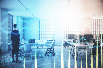Businessman standnig on blurry office interior with forex chart.