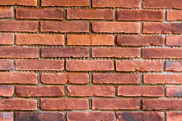 Red brick wall background, dirty textured background with grey cement in seams. Dirty brick wall of red bricks and grey mortar.