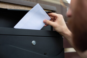Sending, receiving mail. Man putting a letter into a mailbox.