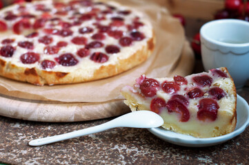 Tart with ripe sweet cherries on wooden circle board on white background. Piece of homemade dessert with ripe sweet cherries. Top view