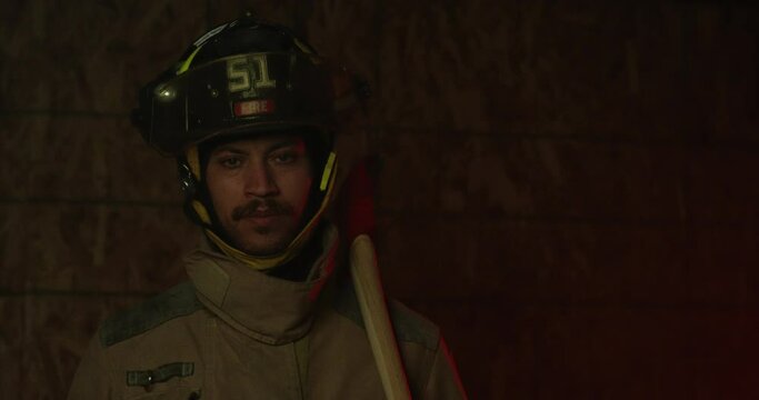 African american fire fighter looks towards camera - axe leaning on shoulder