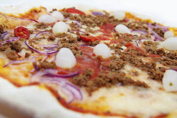 Tasty pizza with meat, tomatoes, chilli peppers, onions and cheese. Pizza isolated on a white background 