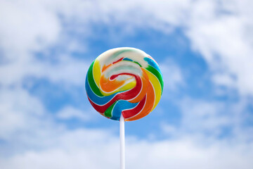Wheel swirl lollipop rainbow with blue sky background.