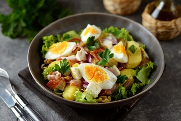 Salad with potatoes, bacon, olives, feta cheese, egg and lettuce.