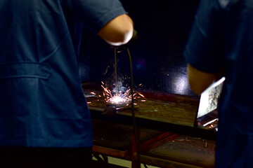 Thai Technologist Steel welding metal In the workshop class with flames and smoke floating out.