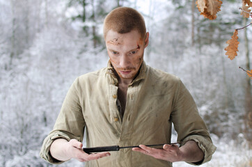 young man in a world war II military uniform with a combat cutlass in his hands in a snowy winter...