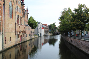 Fototapeta premium Ciudad de Brujas con un canal que pasa al costado de las casas con arboles al otro costado