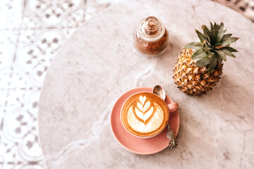 Pink cup of cappuccino on marble table background. Love latte art on the top of it.
