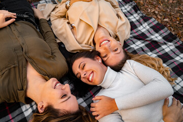 Girlfriends laying on blanket and smiling, having fun, autumn season 