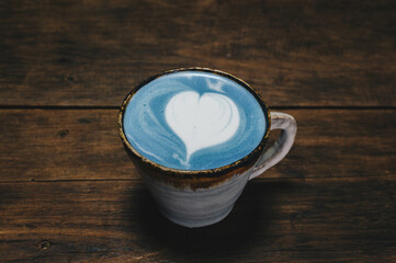 Close-up of a cup of Blue latte on wooden table. The vibrant blue colour of the drink is natural, Made from micro-milled Butterfly Pea Flower, which originated in Thailand.