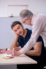 Old teacher and young male student in the classroom