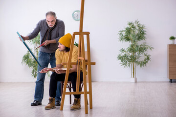 Young man taking lesson from old painter