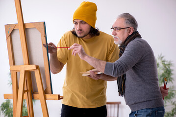 Old man taking lesson from young painter