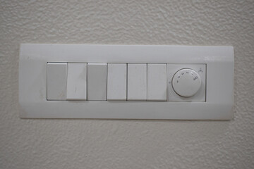 DESIGNER ELECTRICAL WHITE SWITCH BOARD WITH REGULATOR AND SIX SWITCH ON THE WHITE WALL