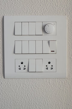DESIGNER ELECTRICAL WHITE SWITCH BOARD WITH REGULATOR AND SWITCHES AND THREE PIN SOCKETS ON THE WHITE WALL