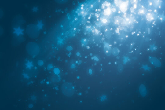 Blue spot light effect with snowflakes light falling and mini glitter floating on blue background