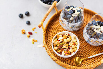 Chia pudding with granola and fresh blueberries in the glasses on a gray concrete background with copy space. Concept of healthy eating, healthy lifestyle, dieting, fitness menu. Selective focus