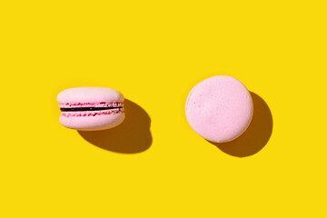 Pink macaroon on yellow colored background, colorful french cookie macaron.