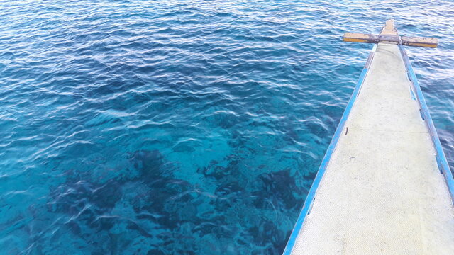 The bow of a boat moving through clear blue sea in The Philippines. © Sinemat