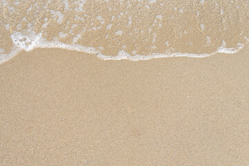 Close up ocean wave bubble on sandy beach. Background for vacation holiday and natural feeling.