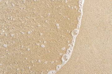Fototapeta na wymiar Close up ocean wave bubble on sandy beach. Background for vacation holiday and natural feeling.