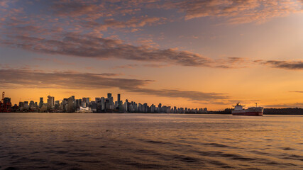 Fototapeta na wymiar Sunset over the Skyline of Downtown Vancouver with a Ocean Freighter moored in the harbor. Viewed from a Harbor Cruise ship in the Vancouver Harbor