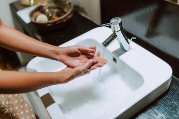 Top view of woman hands while washing hands with soap in the bathroom. Prevention of COVID - 19 coronavirus