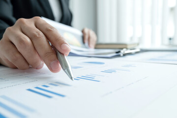 The hands of a male businesswoman are analyzing and calculating the annual income and expenses in a...