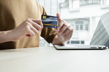 The businessman's hand is holding a credit card and using a laptop for online shopping and internet payment in the office