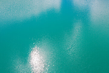 turquoise rippled water surface of quarry lake with sun reflections. drone point view